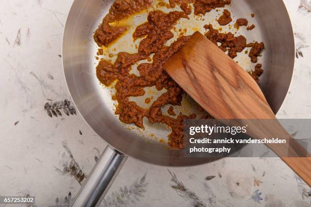 stirring yellow curry paste in olive oil. - curry paste stock pictures, royalty-free photos & images
