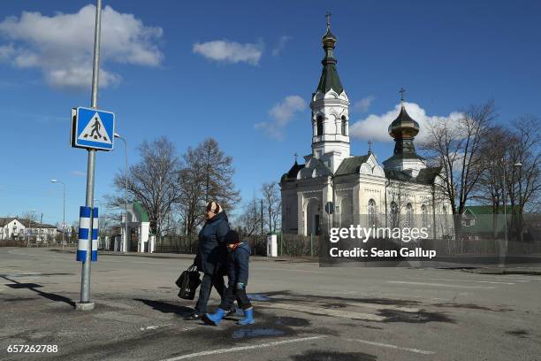 People cross a street as a Russian Orthodox church stands behind on March 23, 2017 in Tapa, Estonia. Estonia is a member of the European Union and...