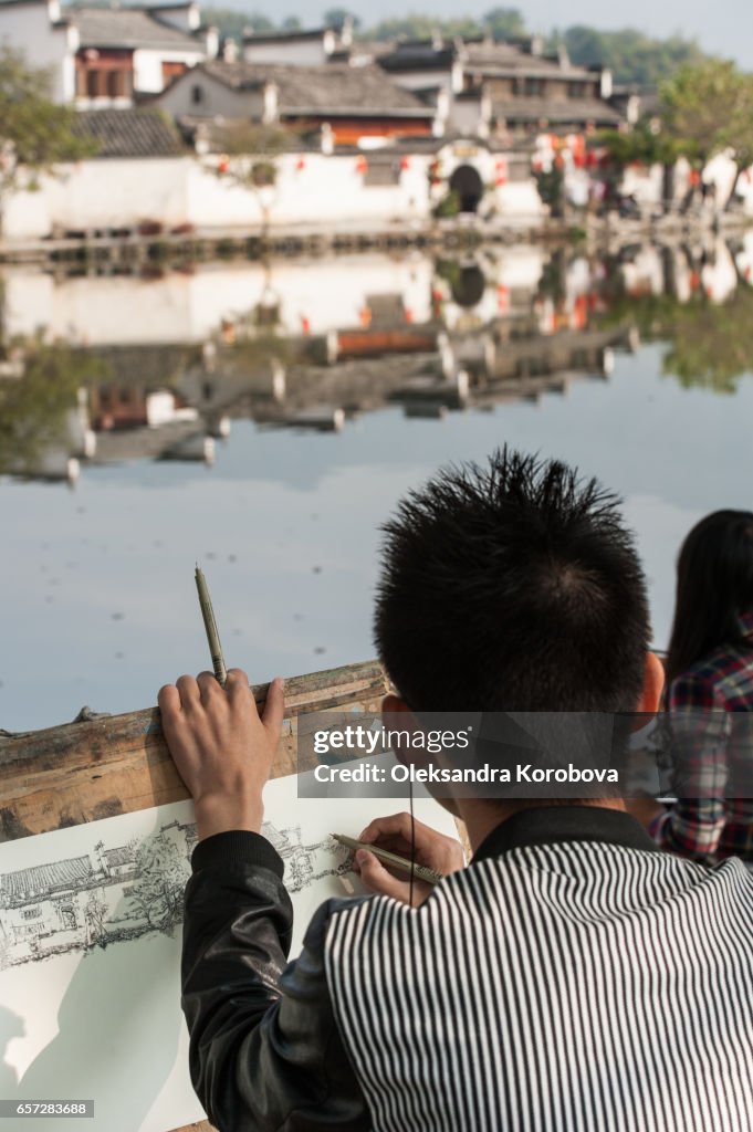 October 18, 2014. Hongcun Village, China. Local students sketching the scenery near an ancient picturesque village that has long enjoyed the name "a village in the Chinese painting"