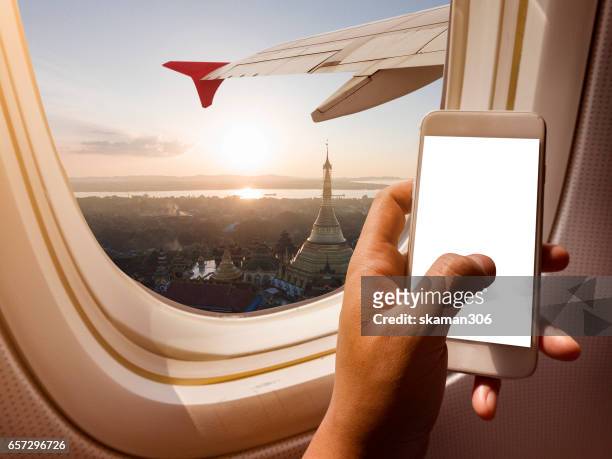 asian man hand holding i phone 6  on board of airplane near window seat and wing with myanma - man with wings flying white background stock pictures, royalty-free photos & images