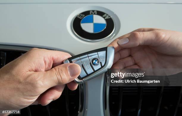 Car purchase - the symbol photo shows the hand of a seller with a BMW car key and the hand of a buyer during the vehicle handover in front of the BMW...