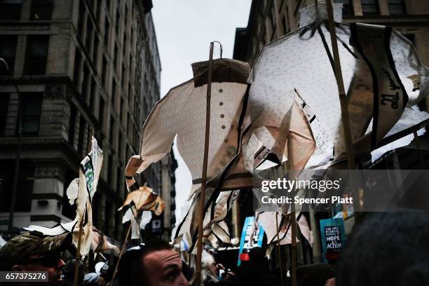 Holding up vintage women's shirts with the names and ages of victims of the Triangle Shirtwaist Factory fire, dozens of people attend a ceremony to...