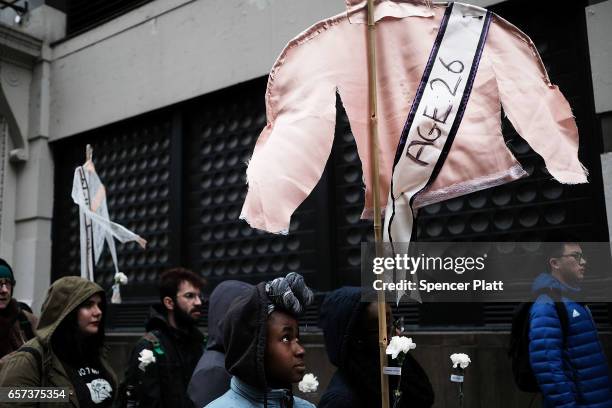 Holding up vintage women's shirts with the names and ages of victims of the Triangle Shirtwaist Factory fire, dozens of people attend a ceremony to...