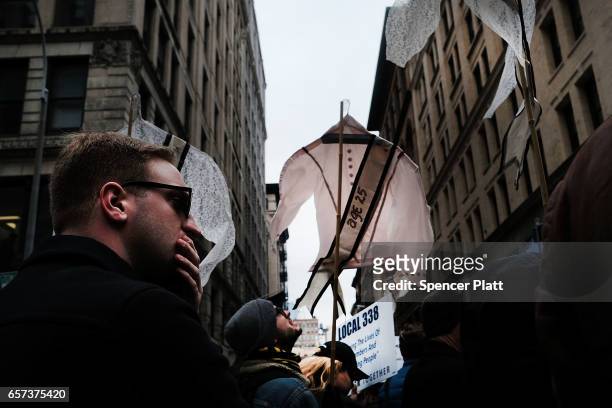Holding up vintage women's shirts with the names and ages of victims of the Triangle Shirtwaist Factory fire, dozens of people attend a ceremony to...
