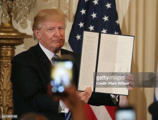 President Donald Trump holds up a proclamation which he signed for Greek Independence Day during a celebration in the East Room of the White House,...