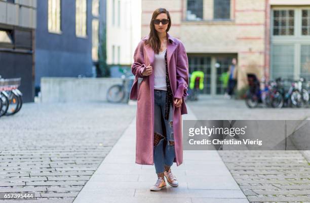 Mayrlou Becker wearing a pink coat with bows, Converse chucks, ripped denim jeans, fishnet tights, sunglasses on March 24, 2017 in Berlin, Germany.