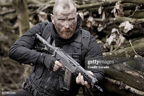 redhead bearded middle aged soldier in military shoot in woodlands - mercenary human role stockfoto's en -beelden