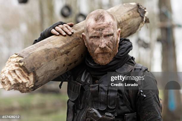 rothaarige bärtige mittlere alter soldat in militärischen schießen in wäldern - überleben stock-fotos und bilder