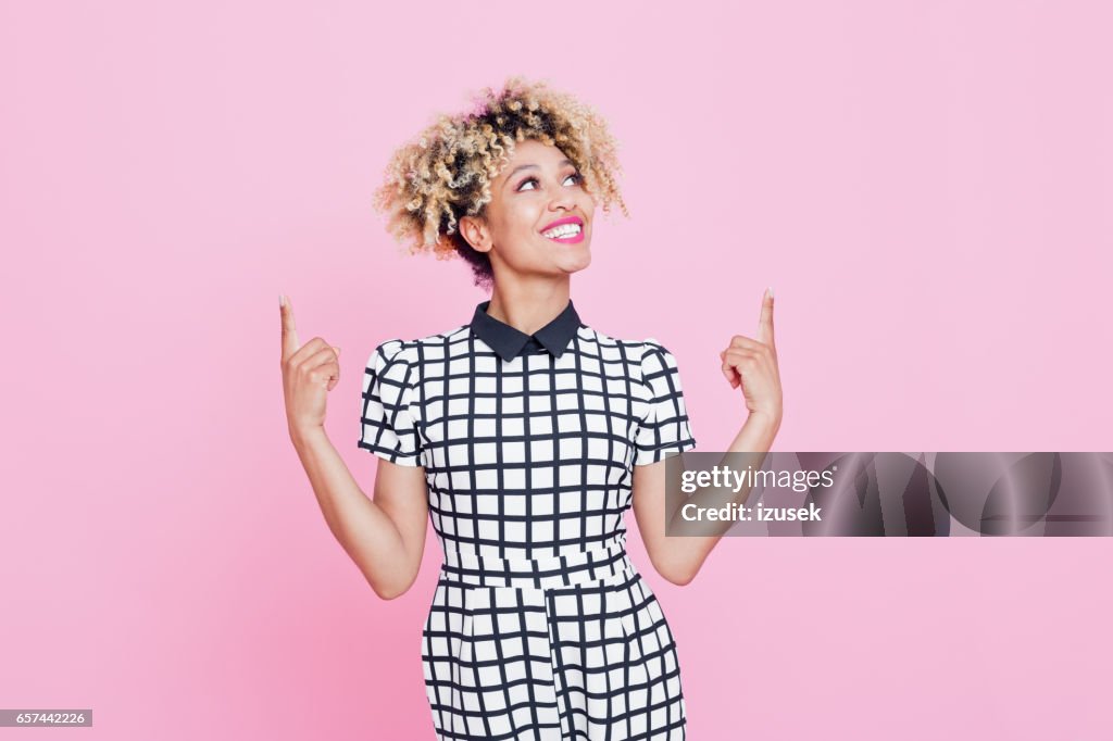 Beautiful afro american young woman pointing at copy space