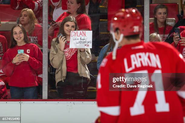 Fan holds a sign as Dylan Larkin of the Detroit Red Wings skates by during warm-ups prior to an NHL game against the Tampa Bay Lightning at Joe Louis...