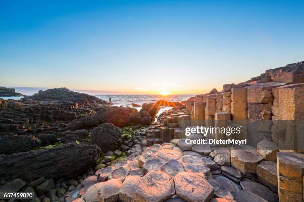 tourist at sunset over giants causeway, northern ireland - ireland coastline stock pictures, royalty-free photos & images