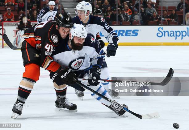 Jared Boll of the Anaheim Ducks battles for the puck against Mark Stuart of the Winnipeg Jets during the game on March 24, 2017 at Honda Center in...