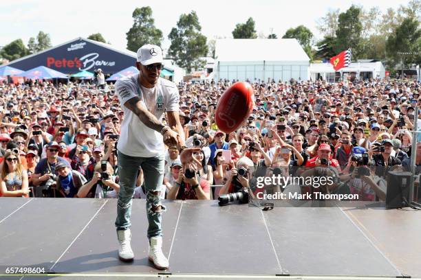 Lewis Hamilton of Great Britain and Mercedes GP throws an AFL ball on the fan stage during final practice for the Australian Formula One Grand Prix...