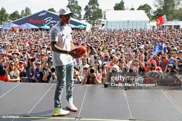 Lewis Hamilton of Great Britain and Mercedes GP throws an AFL ball on the fan stage during final practice for the Australian Formula One Grand Prix...