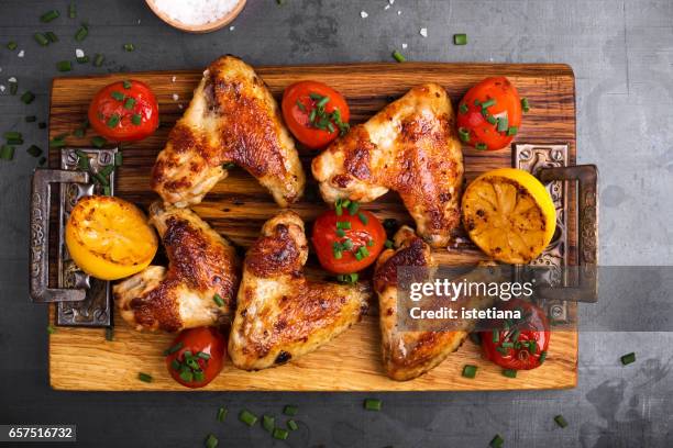 roast chicken wings on cutting board served with lemon and tomatoes - chicken overhead stock-fotos und bilder