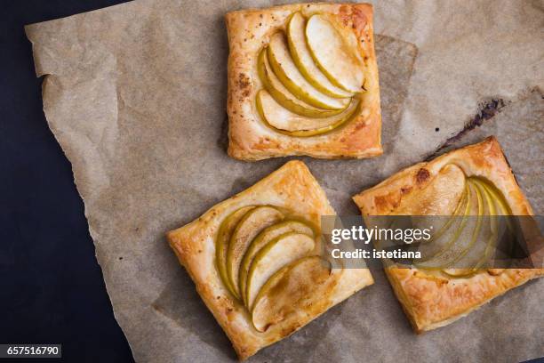homemade puffed pastry apple tarts on baking paper - puff pastry stock pictures, royalty-free photos & images