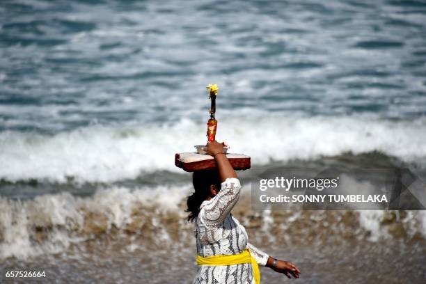 Balinese woman carries an offering on her head for prayers during the Melasti ceremony near Denpasar on the Indonesian resort island of Bali on March...