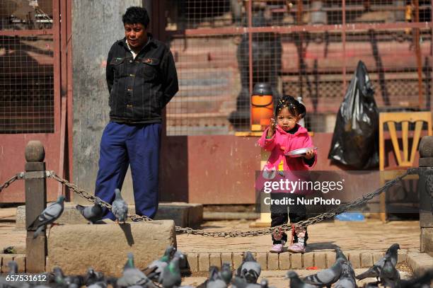 Little girl offering maize grains toward Pigeons at the premises of Patan Durbar Square, Patan, Nepal on Saturday, March 25, 2017.