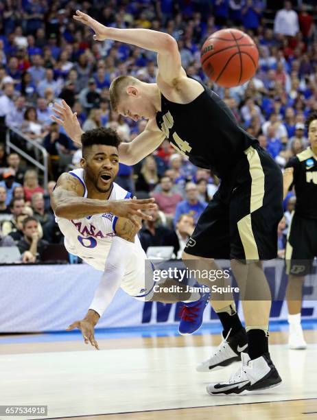 Frank Mason III of the Kansas Jayhawks falls as he passes the ball against Isaac Haas of the Purdue Boilermakers in the first half during the 2017...