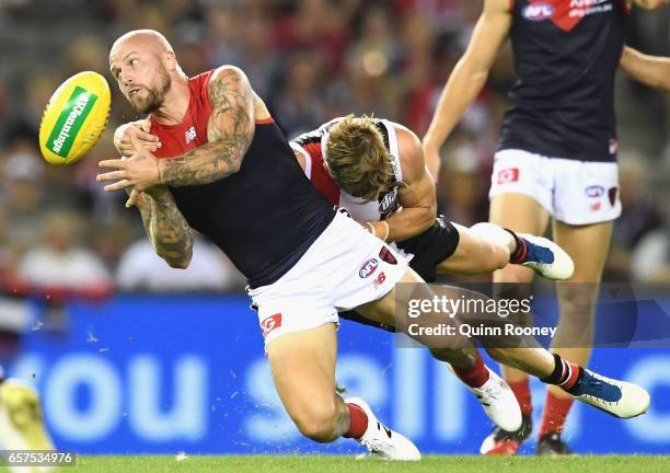 Nathan Jones of the Demons handballs whilst being tackled during the round one AFL match between the St Kilda Saints and the Melbourne Demons at...