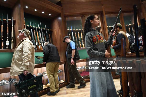 Carissa Phillips, right, holds a firearm in the gun library room during the opening of a new Cabela's store on Thursday March 09, 2017 in...