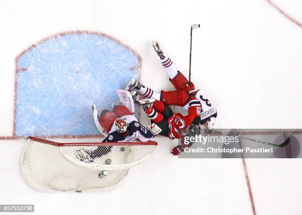 Adam Henrique of the New Jersey Devils is taken down by Josh Anderson of the Columbus Blue Jackets after scoring on Sergei Bobrovsky during the game...