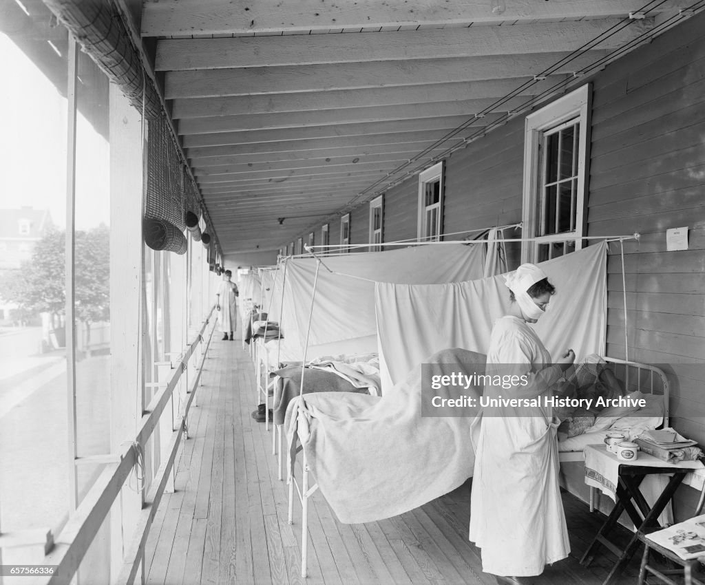 Masked Nurse at the Head of a Row of Beds Treating Patient during Influenza Pandemic, 1918