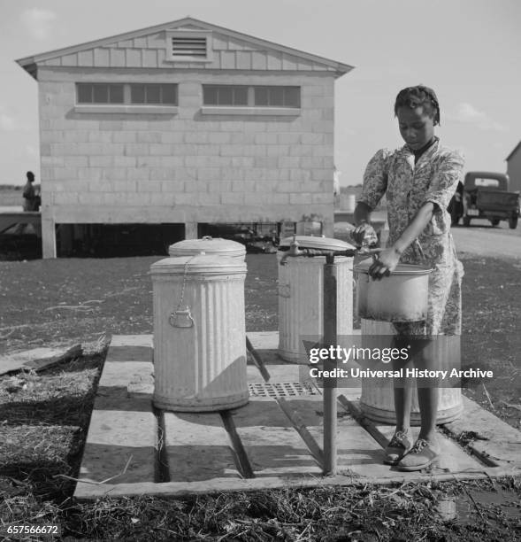 Young Girl Filling Pot with Water, Okeechobee Migratory Labor Camp, Belle Glade, Florida, USA, Marion Post Wolcott for Farm Security Administration,...