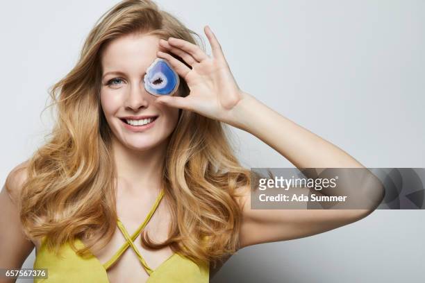 beautiful woman holding a blue colored agate gemstone in front of her face - new age concept photos et images de collection