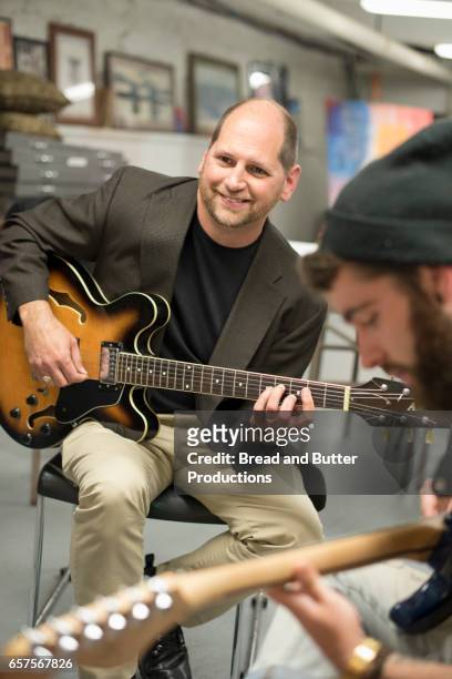 college guitar teacher leading music class with students - bartstoppel stock-fotos und bilder