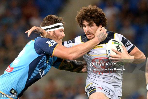 Jake Granville of the Cowboys is challenged by the defence of Chris McQueen of the Titans during the round four NRL match between the Gold Coast...