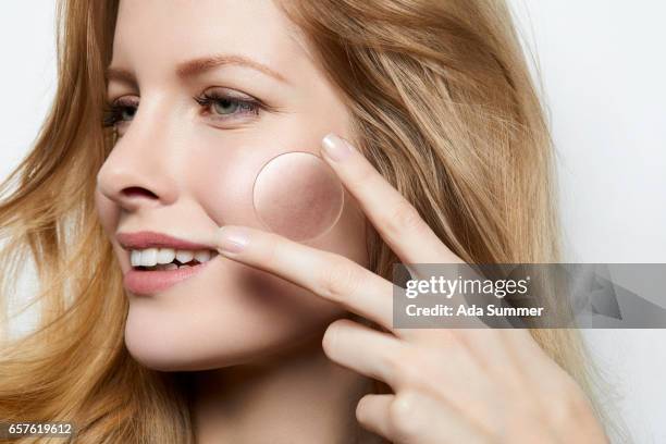 beautiful woman with flawless skin holding a magnifying glass over a part of skin with acne - complexion imagens e fotografias de stock