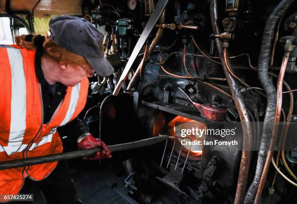 Support crew volunteer Diana Hurfurt rakes the fire of the steam locomotive Royal Scot in Grosmont engine sheds ahead of running between Grosmont and...