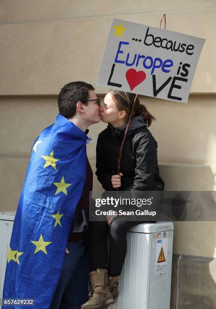 Man wearing a flag of the European Union kisses a young woman holding a sign that reads: ". . . Because Europe is LOVE" at a "March for Europe"...