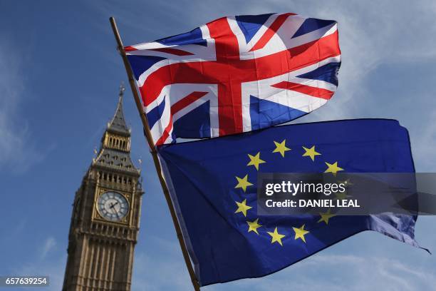 An EU flag and a Union flag held by a demonstrator is seen with Elizabeth Tower and the Houses of Parliament as marchers taking part in an...