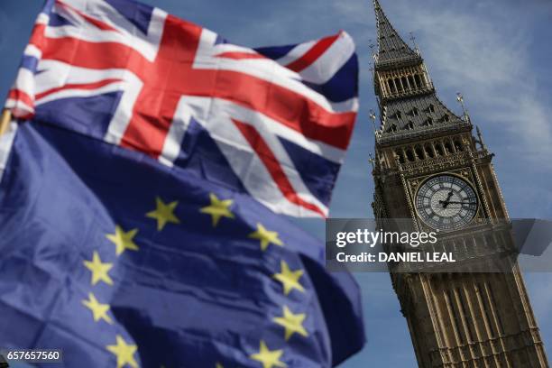 An EU flag and a Union flag held by a demonstrator is seen with Elizabeth Tower and the Houses of Parliament as marchers taking part in an...