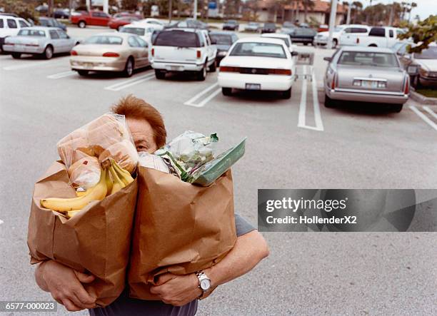 man carrying grocery bags - bolsa de papel fotografías e imágenes de stock