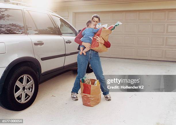 woman with baby and groceries - schleppen stock-fotos und bilder