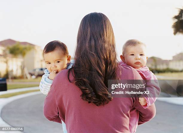 woman holding babies - zwilling stock-fotos und bilder