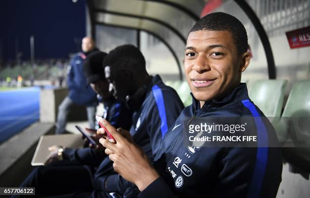 France's forward Kylian Mbappe poses on the bench next to France's forward Ousmane Dembele and France's defender Layvin Kurzawa before the FIFA World...