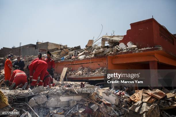 Iraqi civil defense force members work on recovering a dead body buried in the rubble of a home destroyed by reported coalition air strikes in the...