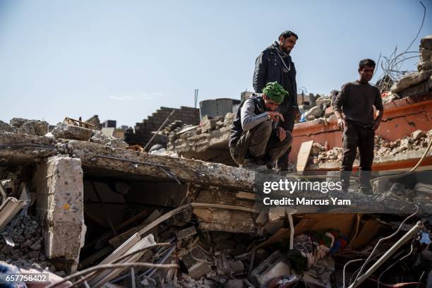 Neighbors and volunteers watch as corpses are getting pulled out of a rubble of a home destroyed by reported coalition air strikes in the al-Jadida...