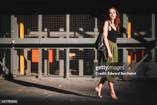 Ophelie Duvillard, model and fashion blogger, wears Steve Madden heels shoes, a Louche green skirt, an Urban Outfitters black low neck sleeveless...