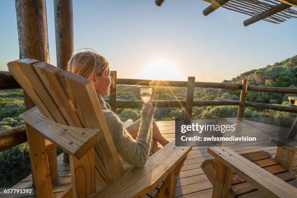 夕暮れ時のテラスでリラックスした若い女性 - cottage ストックフォトと画像