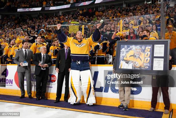 Pekka Rinne of the Nashville Predators raises the silver stick presented to him by GM David Poile for his 500th career NHL game prior to a game...