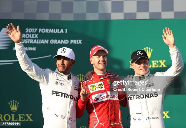 Sebastian Vettel of Germany and Ferrari celebrates his win on the podium with second placed Lewis Hamilton of Great Britain and Mercedes GP and...