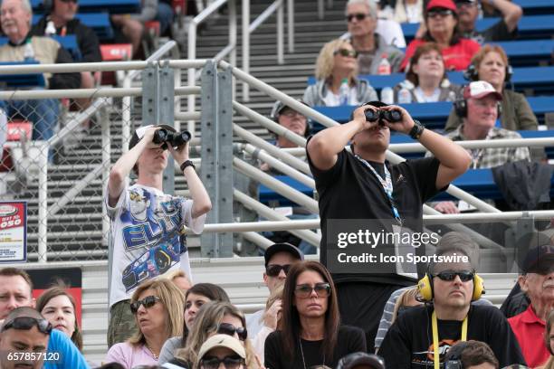 Fans use binoculars to watch the action on the track during the Xfinity Series 19th Annual Service King 300 at Auto Club Speedway in Fontana,...