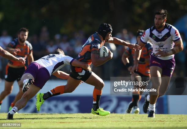 Elijah Taylor of the Tigers is tackled during the round four NRL match between the Wests Tigers and the Melbourne Storm at Leichhardt Oval on March...