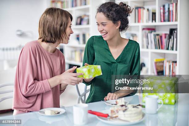 lesbian giving birthday gift to female partner - birthday present stock pictures, royalty-free photos & images