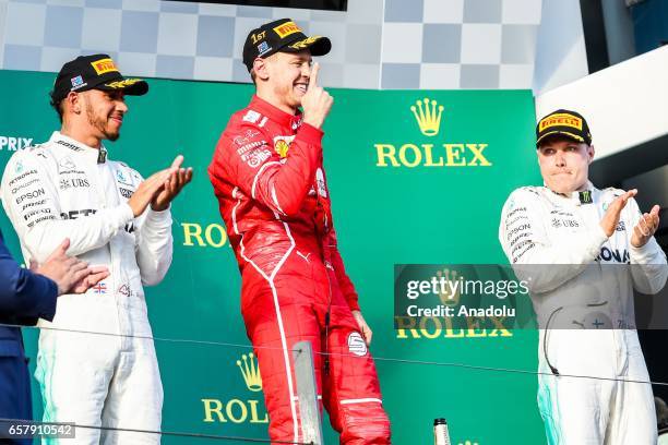 Race winner Sebastian Vettel of Germany, driving for Scuderia Ferrari, celebrates on the podium as 2nd place winner Lewis Hamilton of the United...